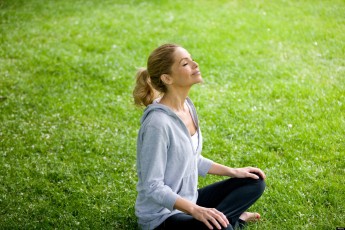 A mid adult woman sitting on the grass